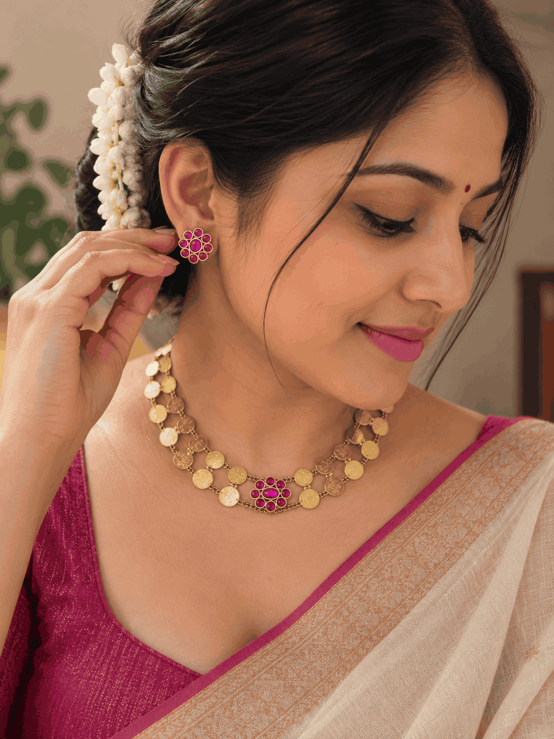 Model wearing antique gold look Kasu Mala coin necklace set with pink stone accents and matching earrings