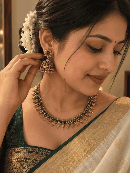 Model wearing antique gold look green stone necklace set with matching jhumka earrings by House of Praniv