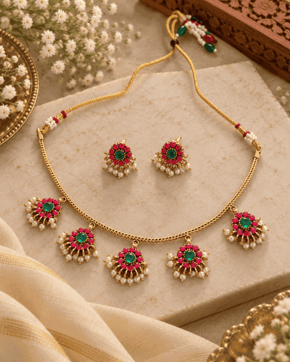 Gold look floral necklace set with pink and green stones, pearl-like drops and matching earrings displayed flat
