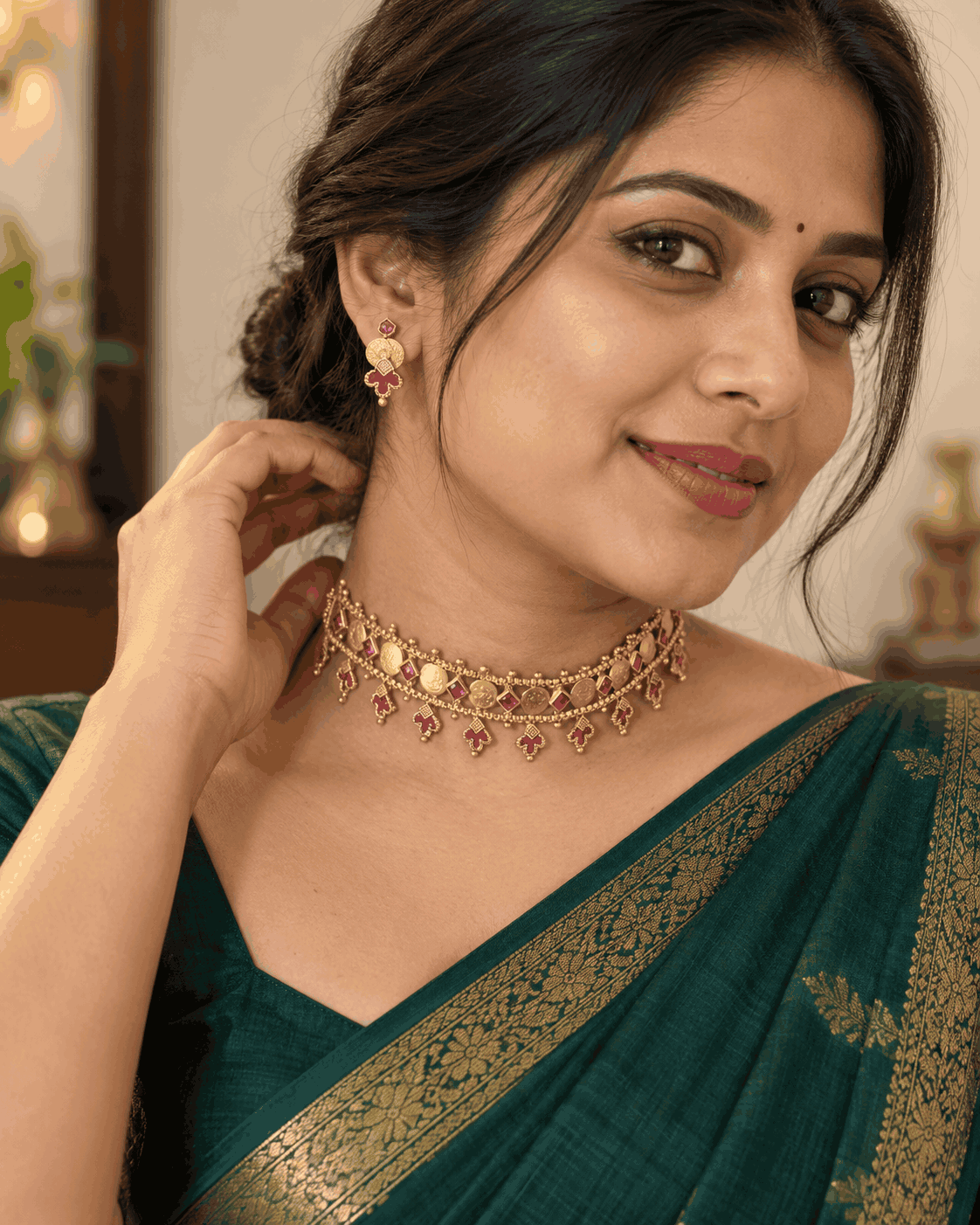 Model wearing antique gold look coin choker necklace set with pink stones and matching earrings by House of Praniv