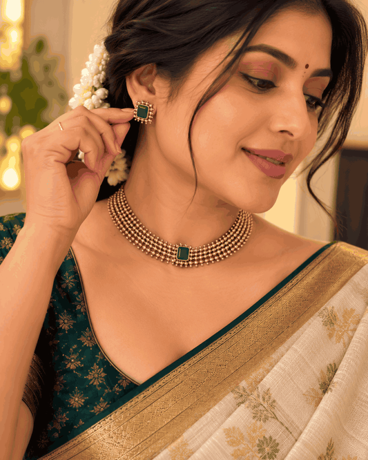 Model wearing antique gold look green stone beaded necklace set with matching green stone stud earrings