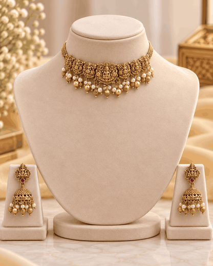 Antique gold look Lakshmi temple choker displayed on mannequin with intricate traditional motifs and pearl-like bead drops.