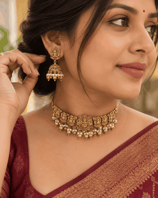 Model wearing antique gold look Lakshmi temple choker necklace with pearl-like drops and matching jhumka earrings by House of Praniv.