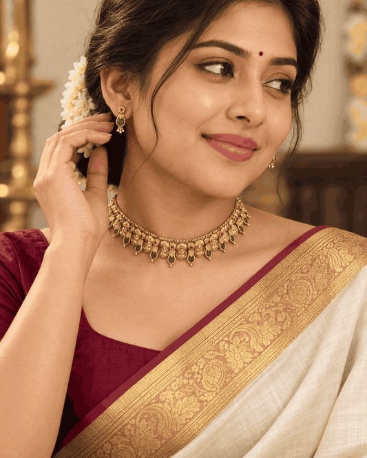Model wearing antique gold look Lakshmi coin choker with green teardrop stones and matching earrings by House of Praniv.