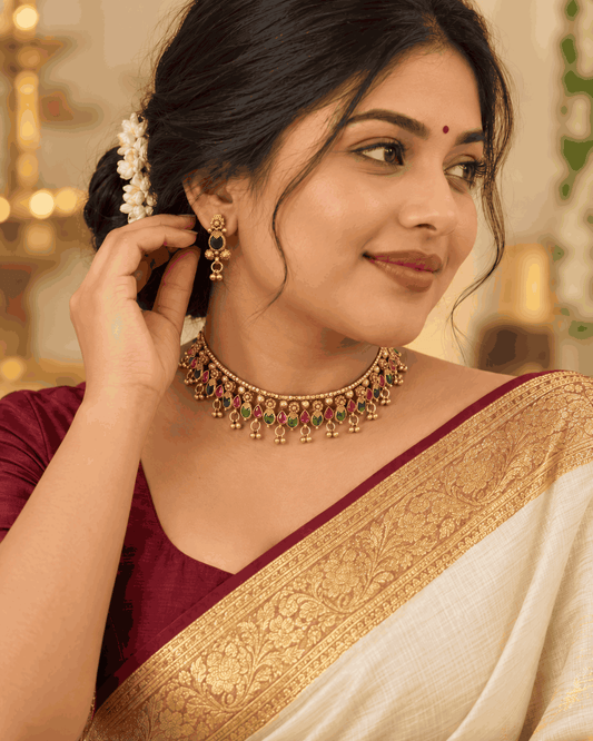 Model wearing antique gold look pink and green stone choker set with ghungroo drops and matching earrings