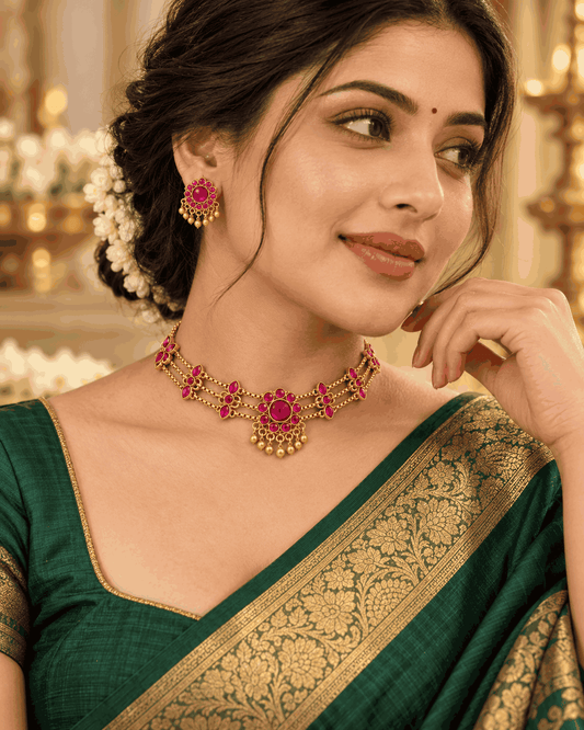 Model wearing gold look pink stone floral choker necklace set with triple-layer chains and matching earrings by House of Praniv.