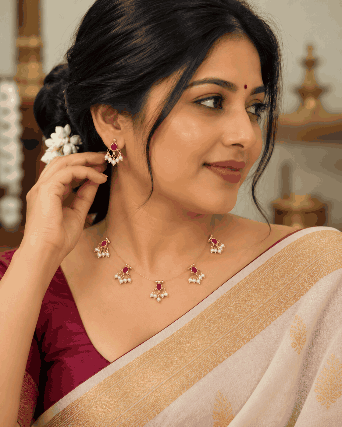 Model wearing delicate invisible chain necklace with pink stone motifs, pearl-like drops and matching pink earrings.